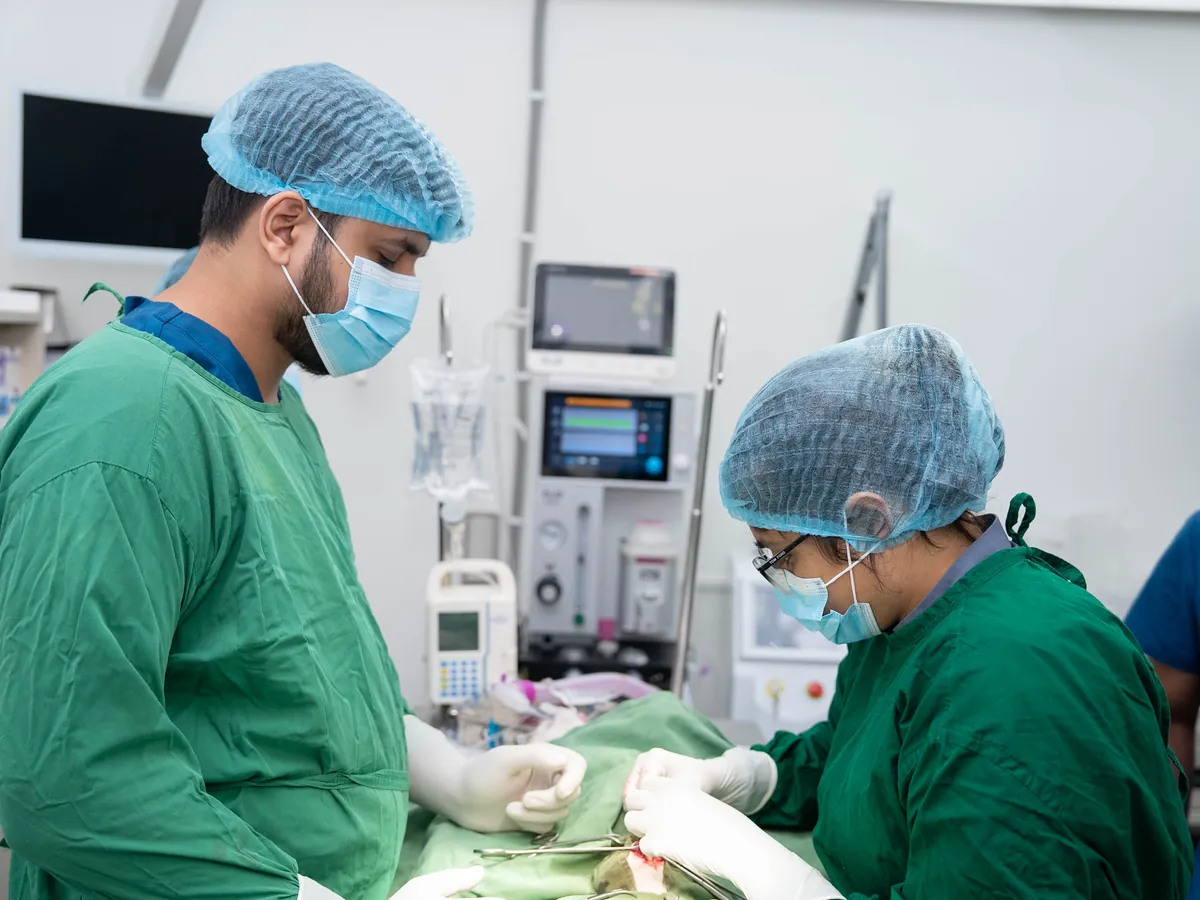 Two surgeons in green scrubs operating in the surgical theatre